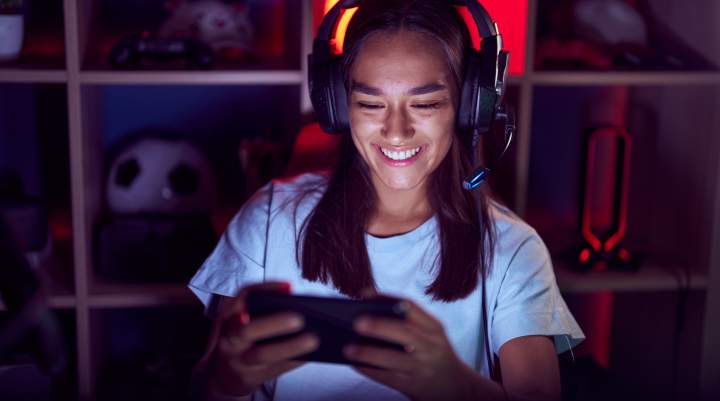 A woman happily gaming on her smartphone.