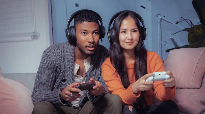 A young man and woman gaming together on Xbox from their living room.