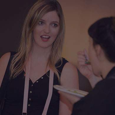 a blonde lady looking surprised at a person eating food from a fork